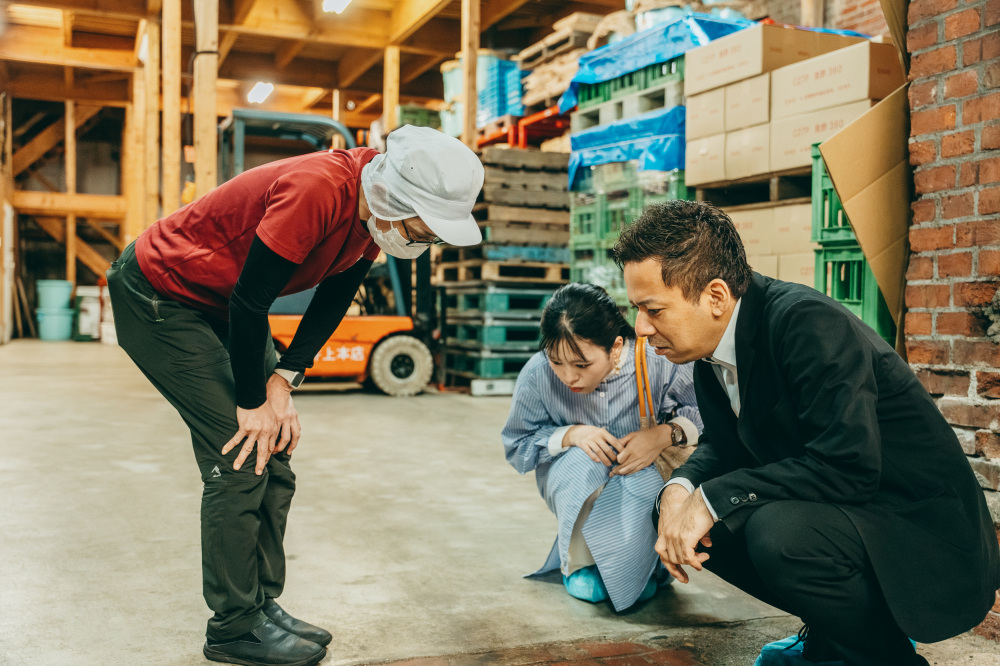 しゃがんで何か探している3人。レンガに製造会社のロゴが刻印されていないか調べています