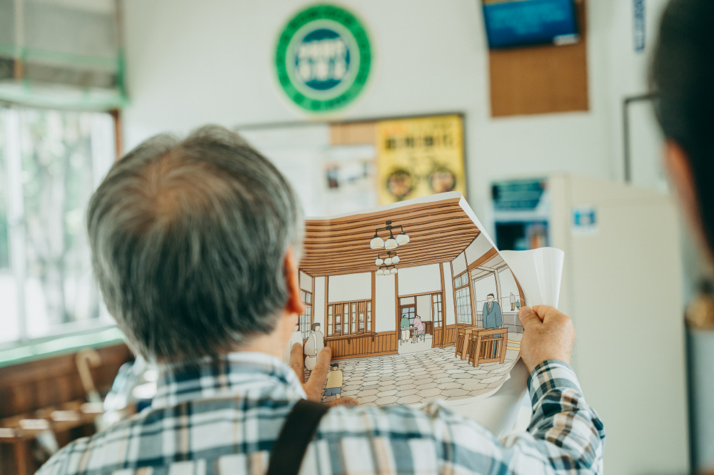 復原完成予定図を見せてくれる木原さん。往時の姿への復原が待ち遠しい